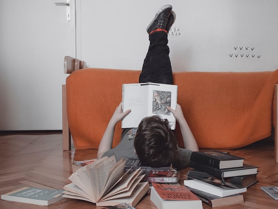 Photo by Anita Jankovic woman reading book on orange sofa